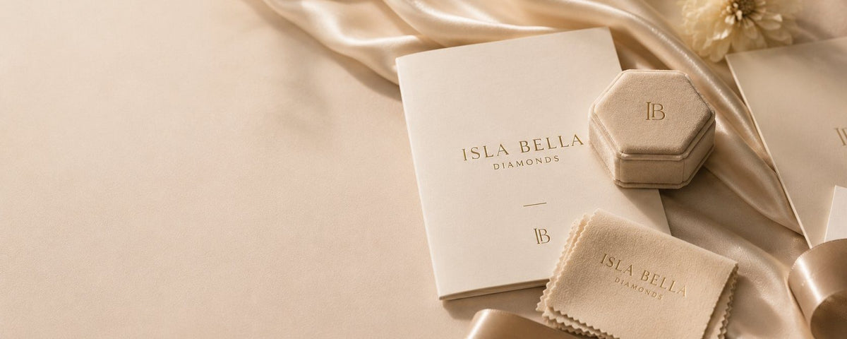 Isla Bella Diamonds luxury packaging — a hexagonal ring box, branded gift folder and polishing cloth resting on champagne silk.